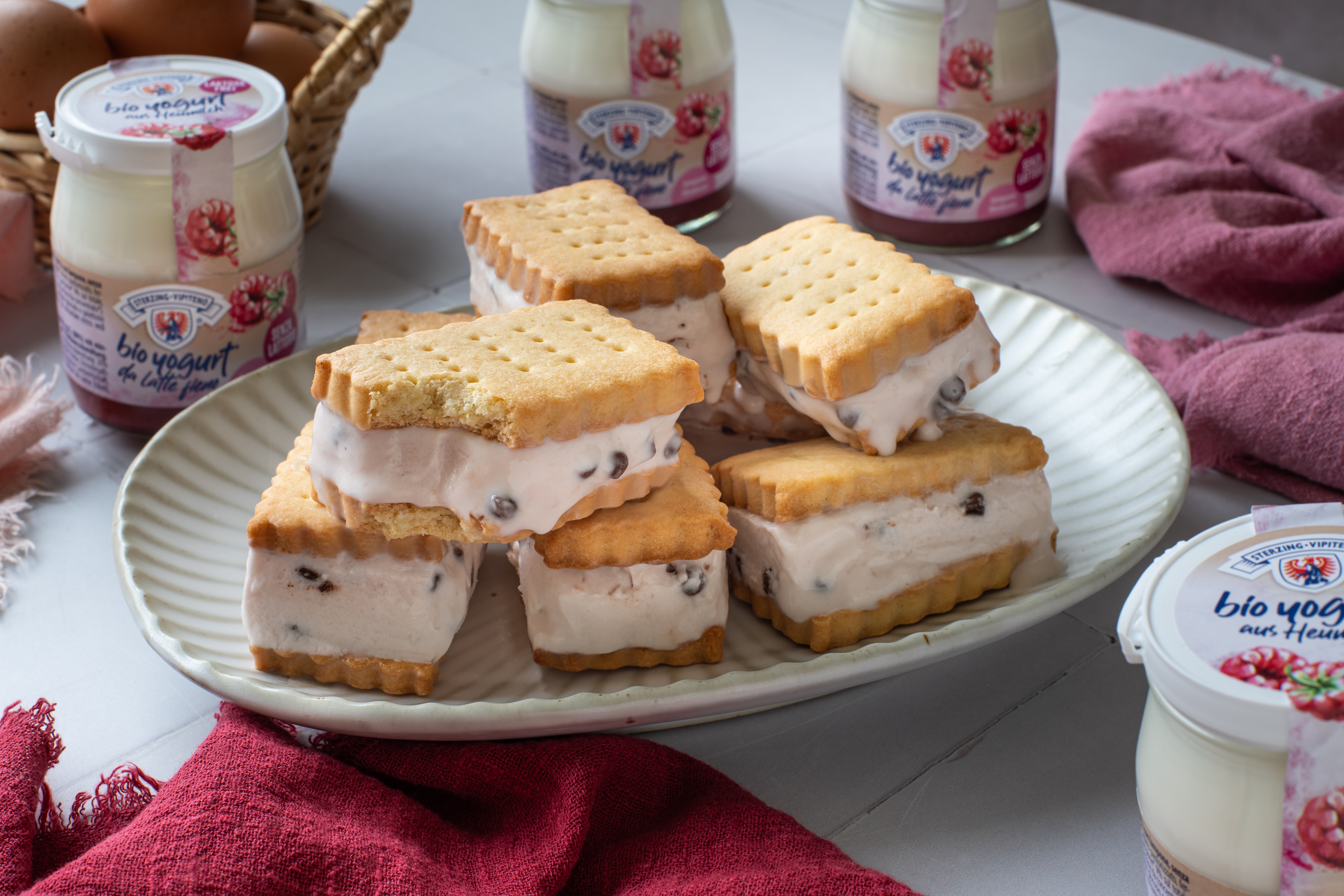 Mehrere eckige Eis-Sandwiches mit Joghurt-Eis und Schokoladentropfen auf einem weißen Teller