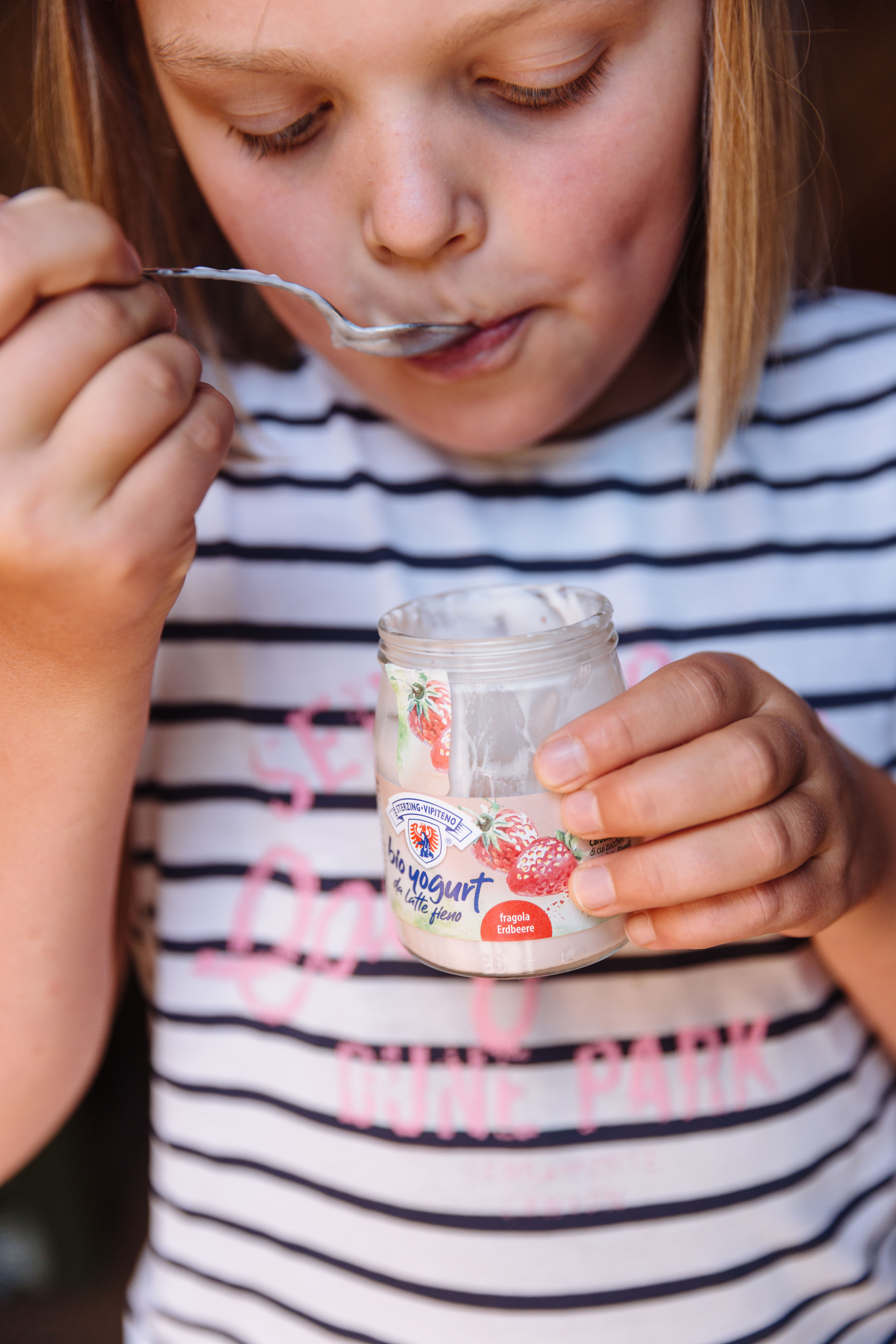 Mädchen isst Joghurt im Glas