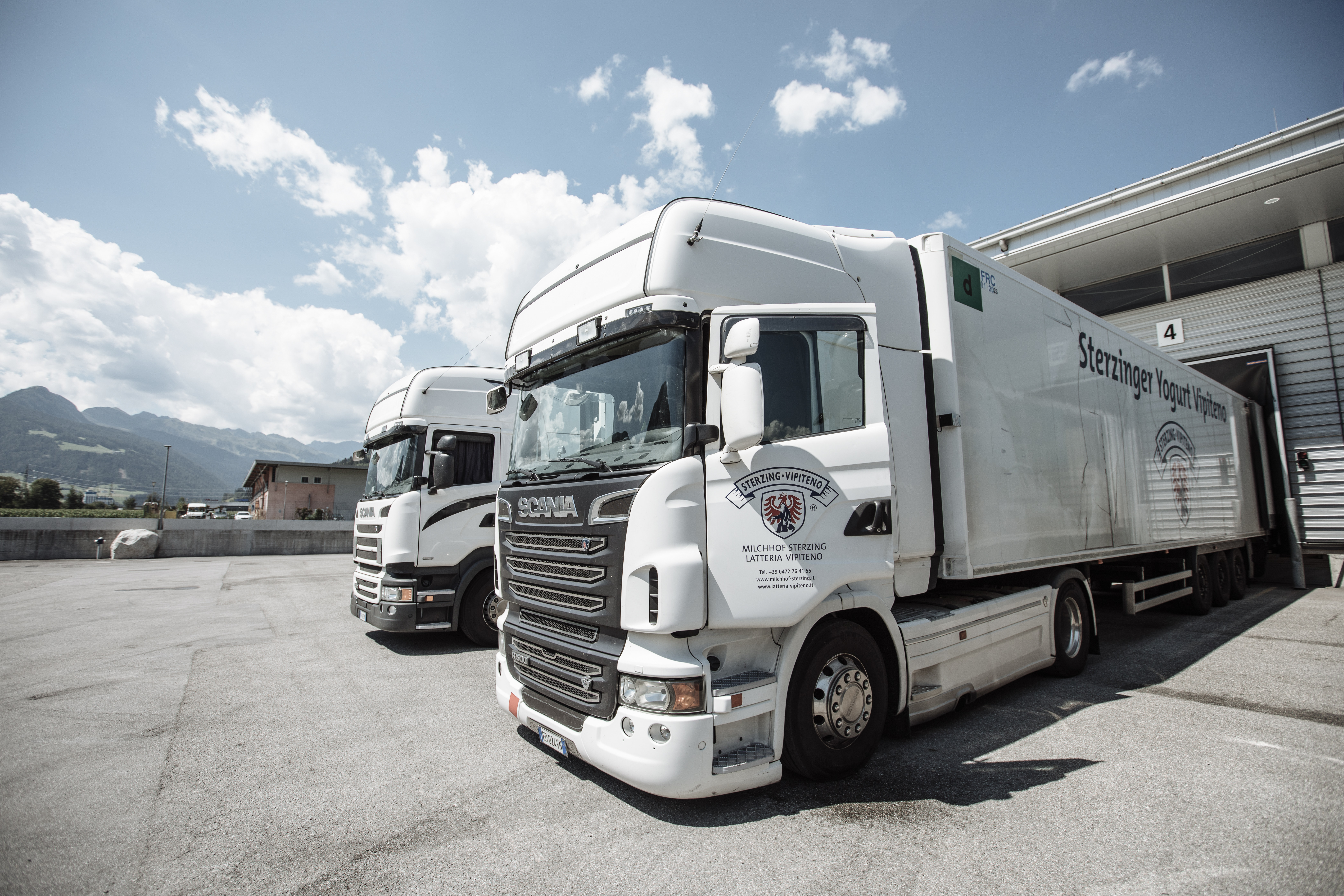 Zwei Liefer-LKW stehen vor einer Laderampe eines Logistikzentrums