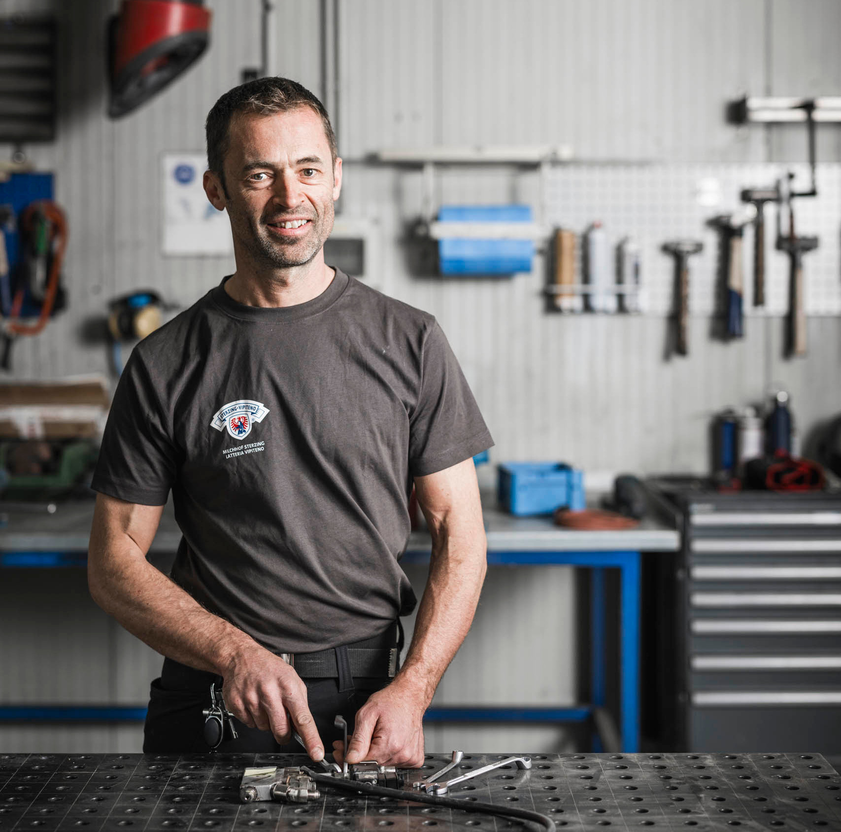 Mitarbeiter von Milchhof Sterzing arbeitet an Metallbauteilen auf einem Arbeitstisch